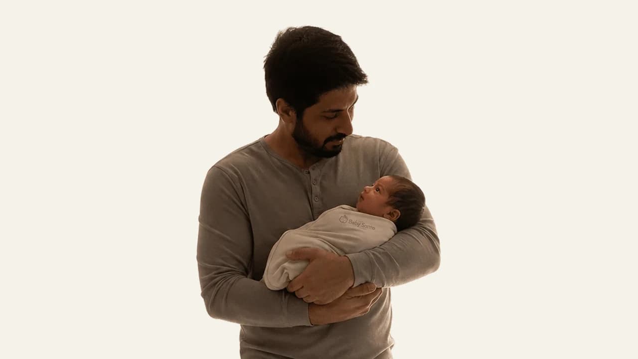 A calm baby quietly awake with a parent in a dimly lit room at night