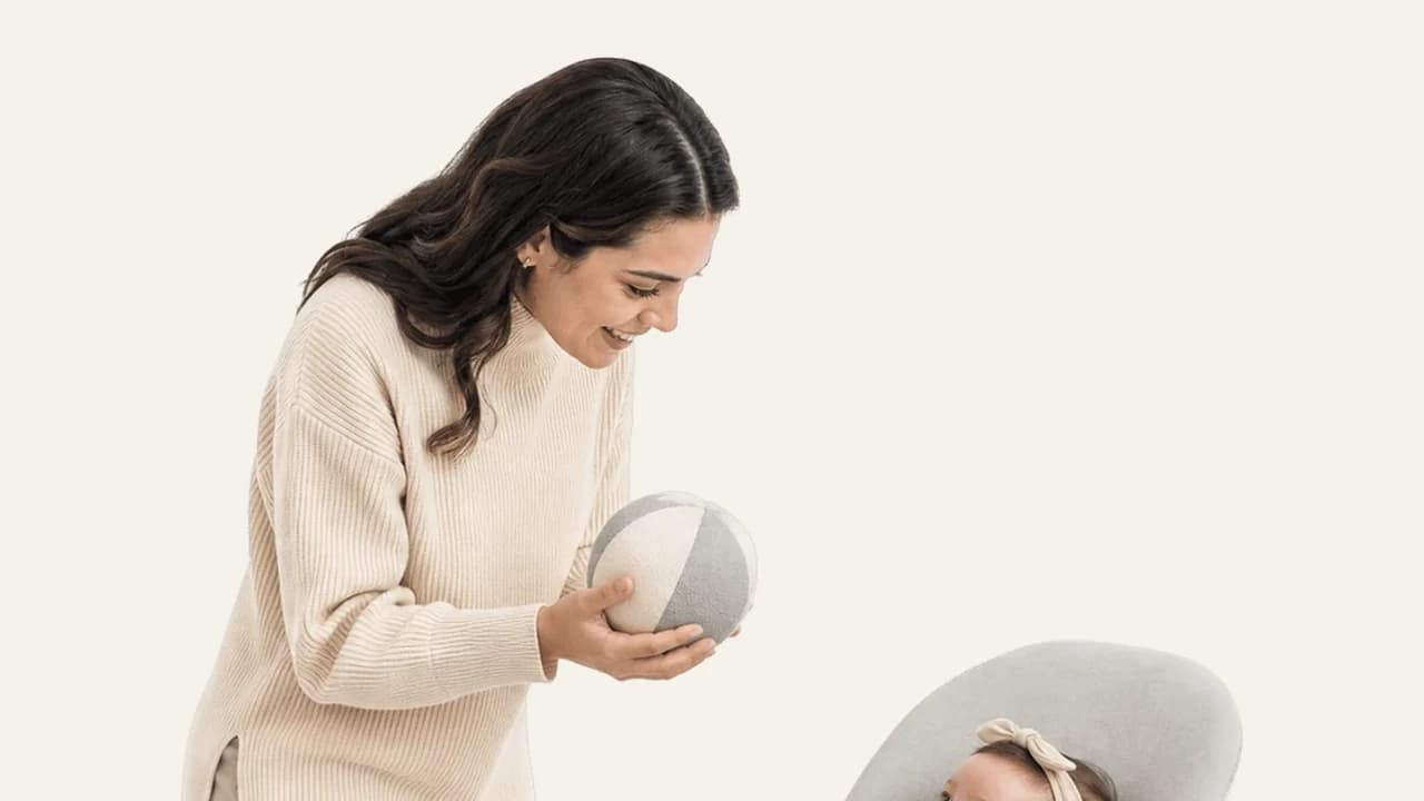 A five month old baby grasping a toy with both hands before a nap